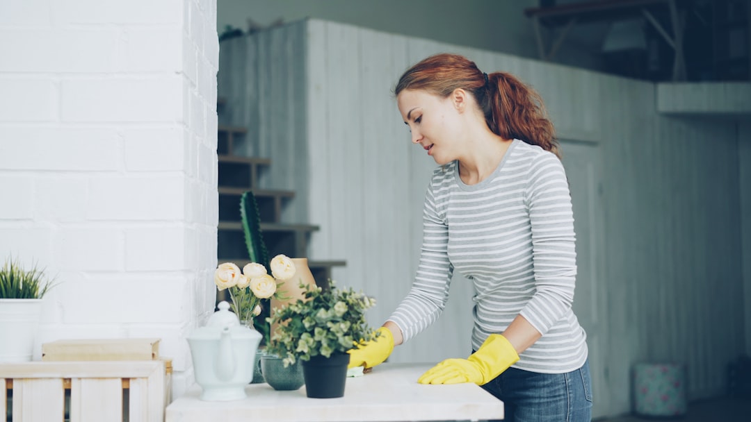gallery-04 Cheerful young maid is dusting the furniture holding wet cloth in modern light apartment. Housework, people and interiors concept.